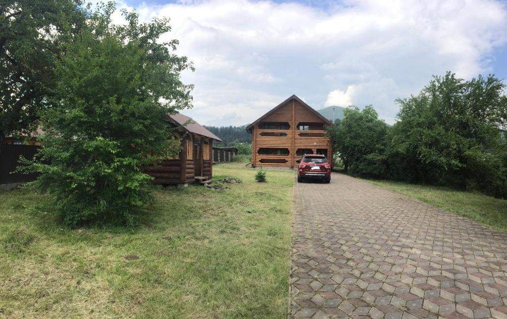 a log cabin with a car parked next to a road at Приватний котедж «Наш Черемош», с.Ільці in Iltsi