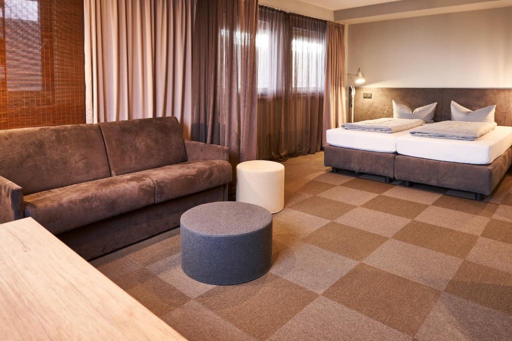 a hotel room with a couch and a bed at ARRIVEL Hotel Kirchheim in Kirchheim
