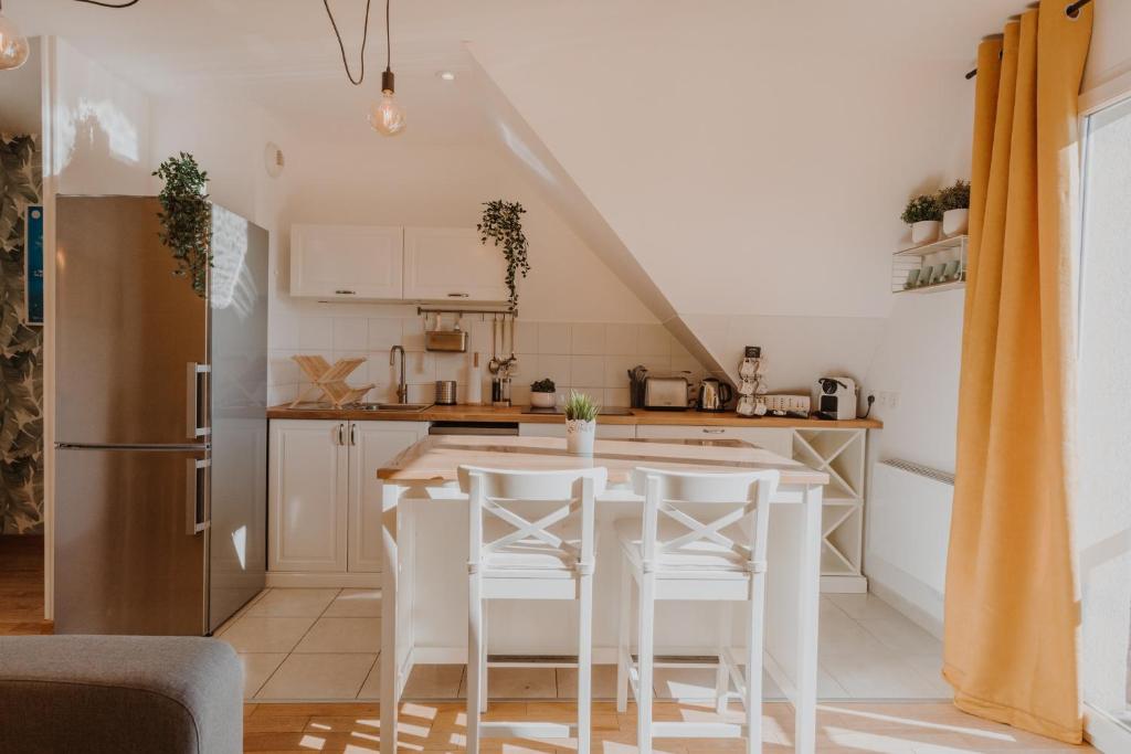 una cucina con tavolo e alcuni sgabelli bianchi di Appartement 2 chambres aux portes de Deauville 100m du Pôle International du cheval a Saint-Arnoult