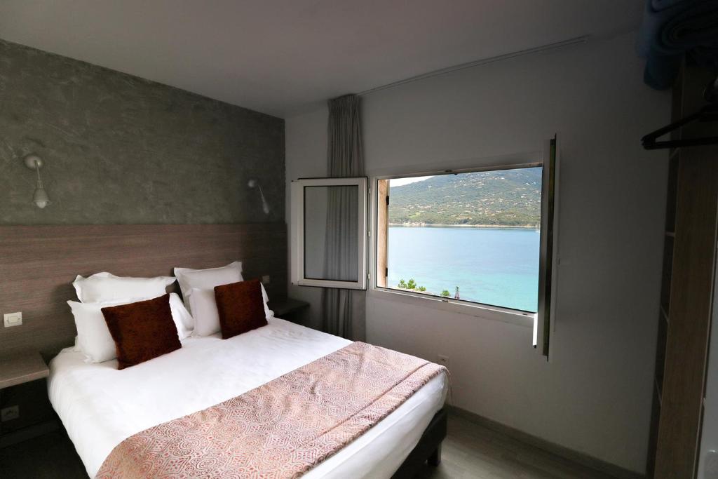 a bedroom with a large bed and a window at Hôtel Sampiero Corso in Propriano