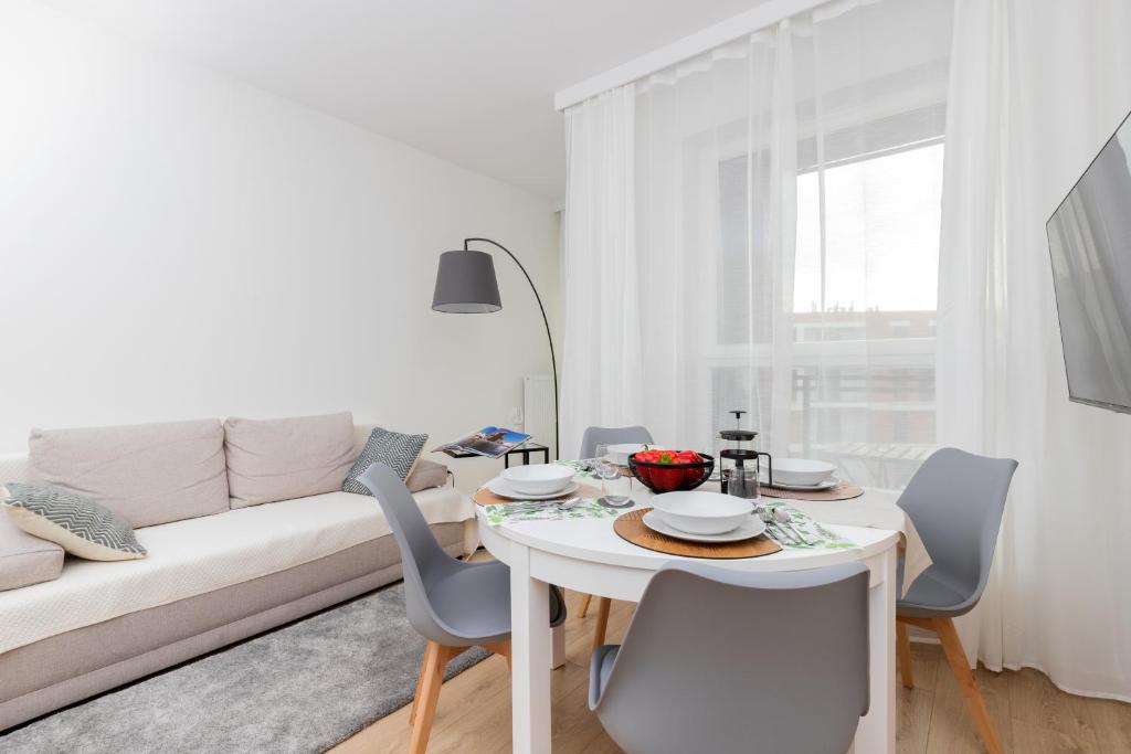 a white living room with a white couch and a table and chairs at Baltic Nomad Studio Bastion Walowa Old Town by Renters in Gdańsk