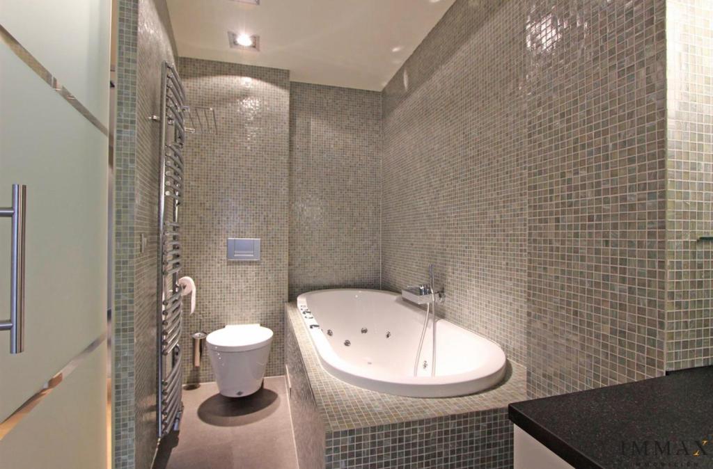 ein Badezimmer mit einer Badewanne, einem WC und einem Waschbecken in der Unterkunft Appartement Sunny home Deluxe in Knokke-Heist
