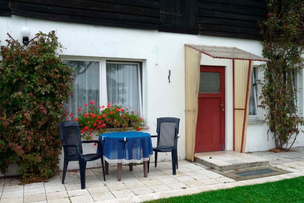 tavolo e sedie di fronte a una casa con porta rossa di Ferienwohnung Tor zur Ostsee - a55964 a Mellenthin