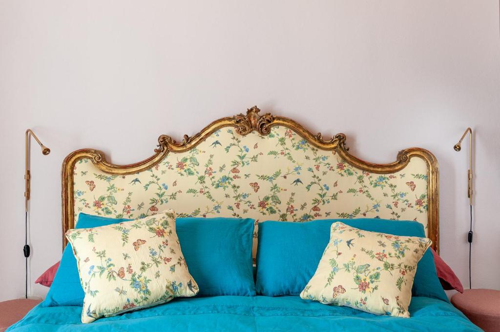 a blue bed with a floral headboard and two pillows at Ca' Maggiolina B&B in Milan