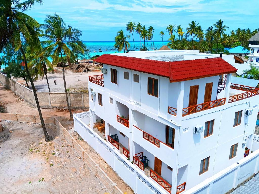 - un bâtiment blanc avec un toit rouge à côté de la plage dans l'établissement Zanzicrown, à Nungwi