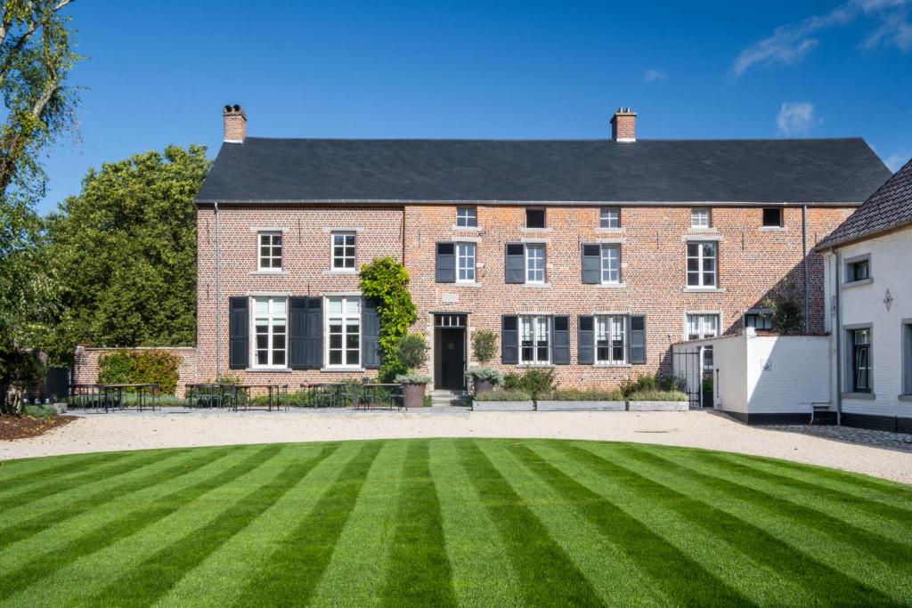 une grande maison en briques avec une grande pelouse verte dans l'établissement B&B Sterckxhof, à Meise