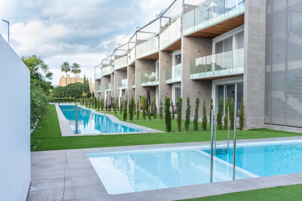 een appartementencomplex met een zwembad naast een gebouw bij Apartamento Ático Estrasburgo suites in Jávea