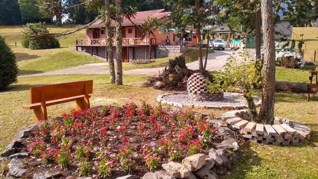 a garden with flowers and a bench in front of a house at PARADOURO BOCA DA SERRA in São Francisco de Paula