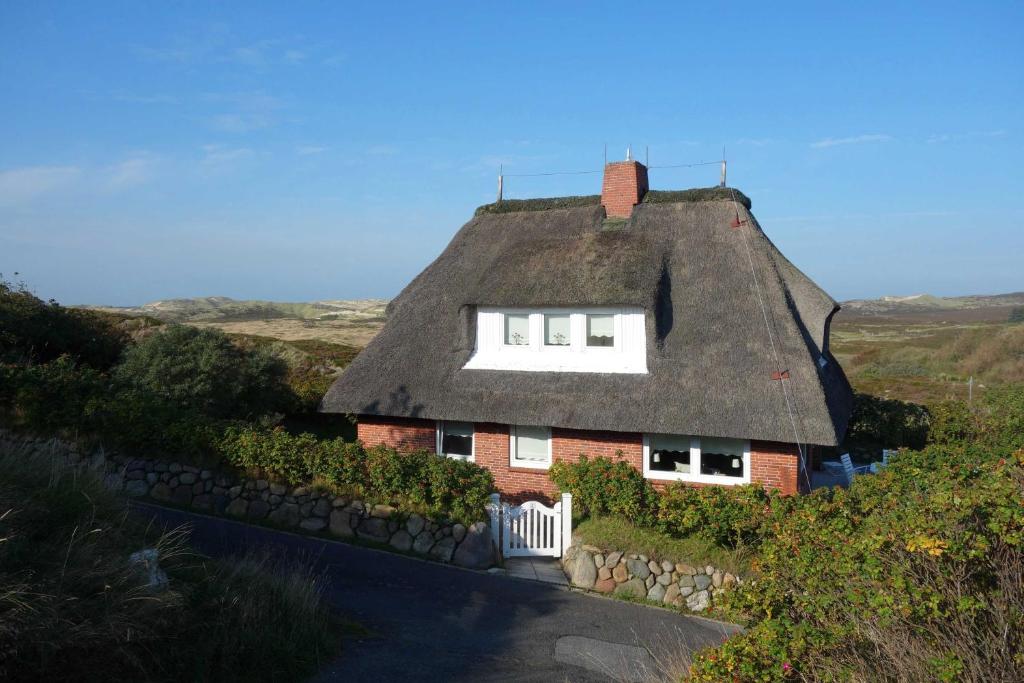 een huis met een rieten dak en een wit raam bij Haus Meerblick in List