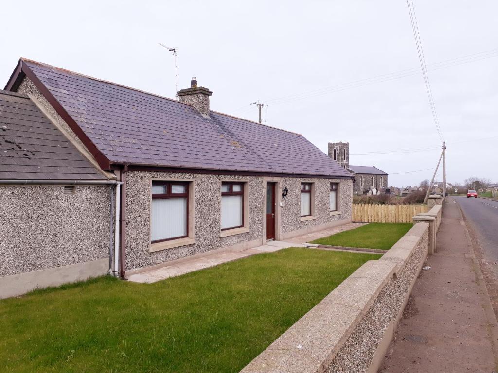 a house with a green lawn in front of it at Jenny's Farm Cottage, Giant's Causeway in Dunseverick