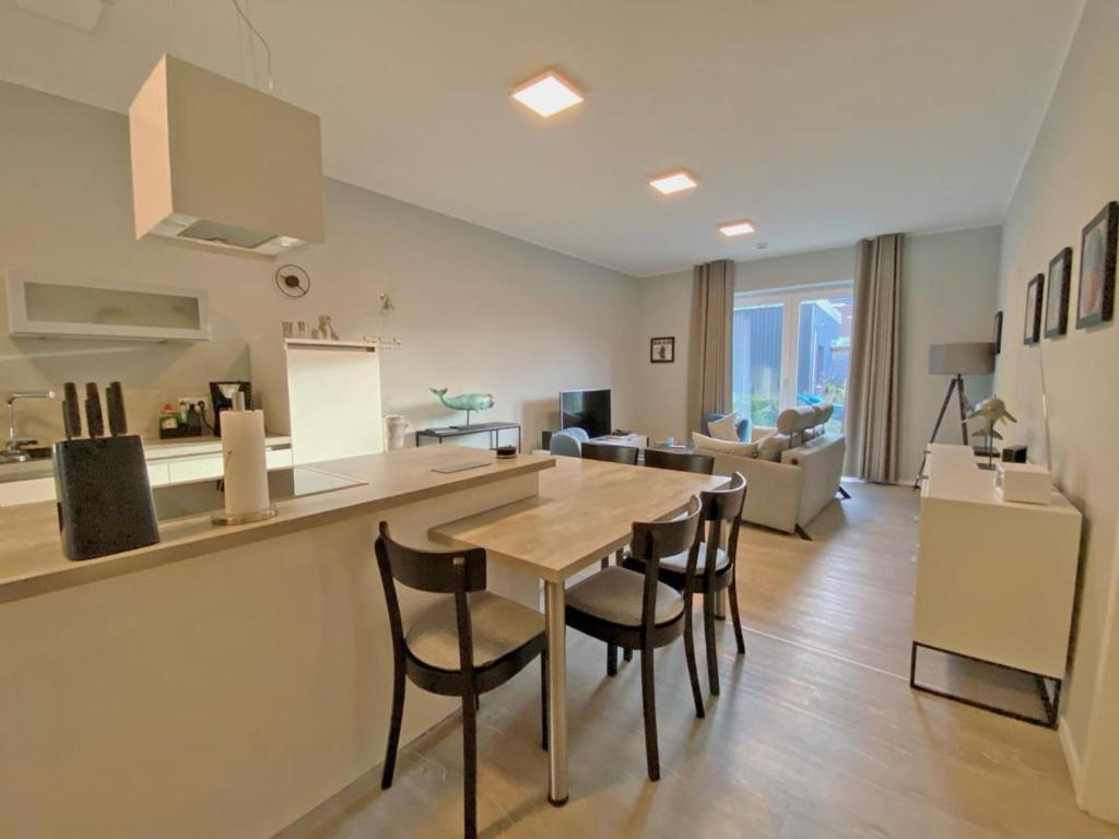 a kitchen and living room with a table and chairs at Sonnengarten 3 - KüstenART in Kellenhusen