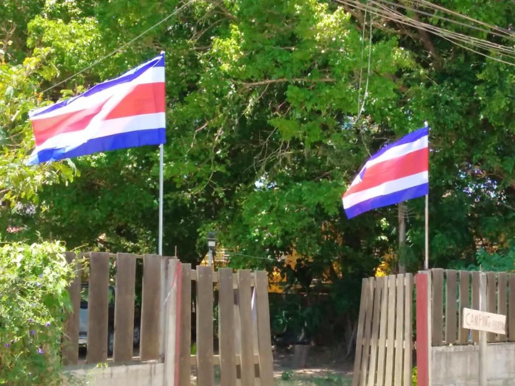 two flags flying over a wooden fence at Hospedaje Combi dream bird in Guanacaste