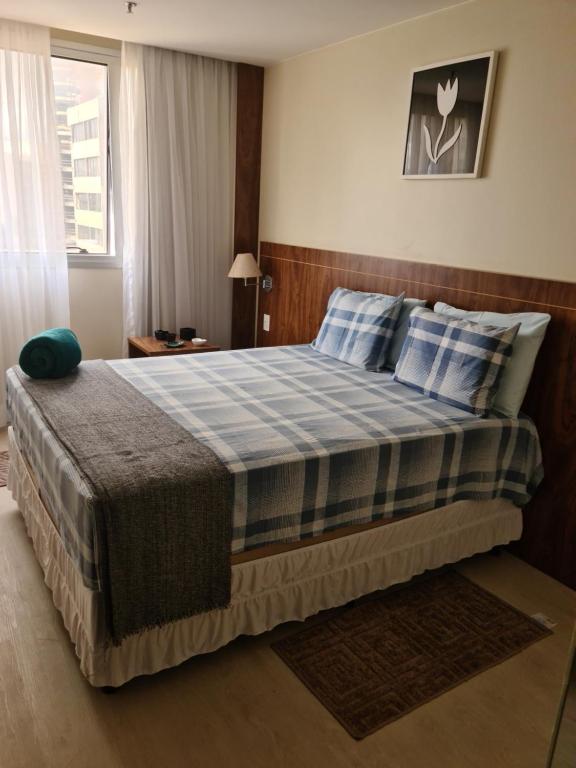 a bedroom with a large bed with blue and white pillows at Flat maravilhoso no Centro de Taguatinga - Pistão Sul in Taguatinga