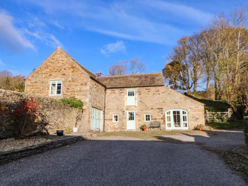a large stone house with a driveway at The Barn in Bishop Auckland