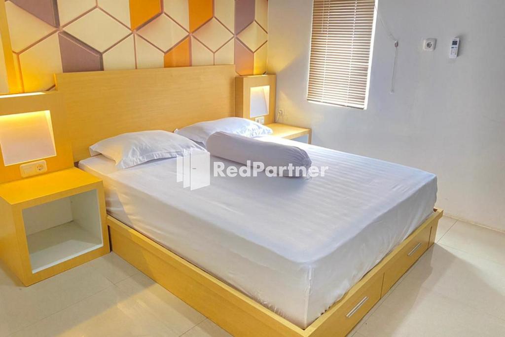 une chambre avec un grand lit avec une tête de lit en bois dans l'établissement Homestay Syariah Callista Bantaeng Mitra RedDoorz, à Bombong