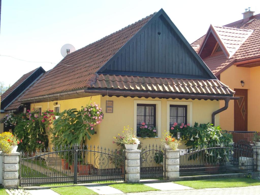 een geel huis met een zwart dak en een hek bij Chalupa Kucbel in Liptovská Teplá