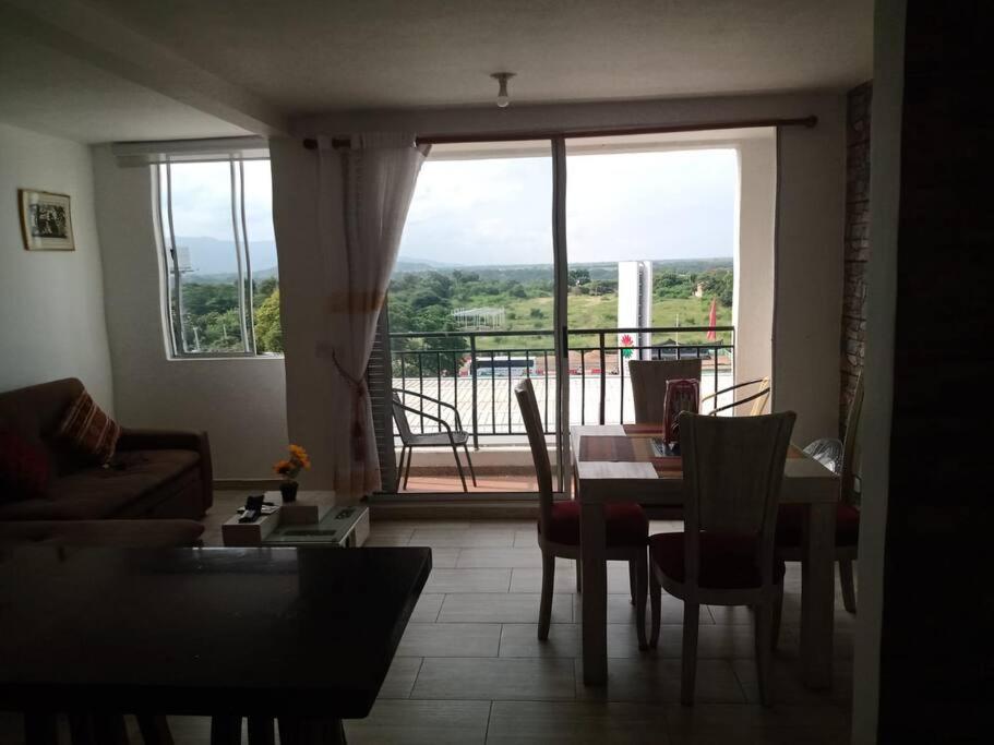 ein Wohnzimmer mit einem Tisch und Stühlen sowie einem großen Fenster in der Unterkunft Hermoso apartamento Ricaurte in Ricaurte