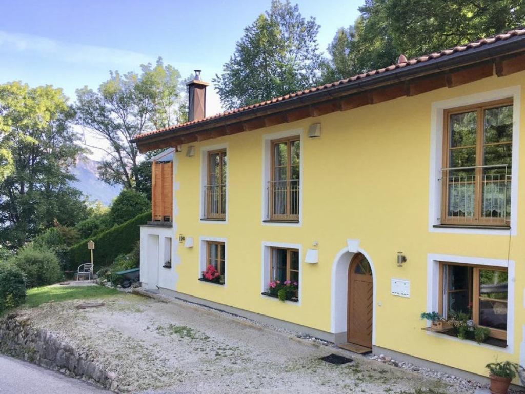 ein gelbes Haus mit Fenstern und einer Einfahrt in der Unterkunft FeWo Hansl`s Freiraum - Berchtesgaden - Schönau am Königssee in Schönau am Königssee