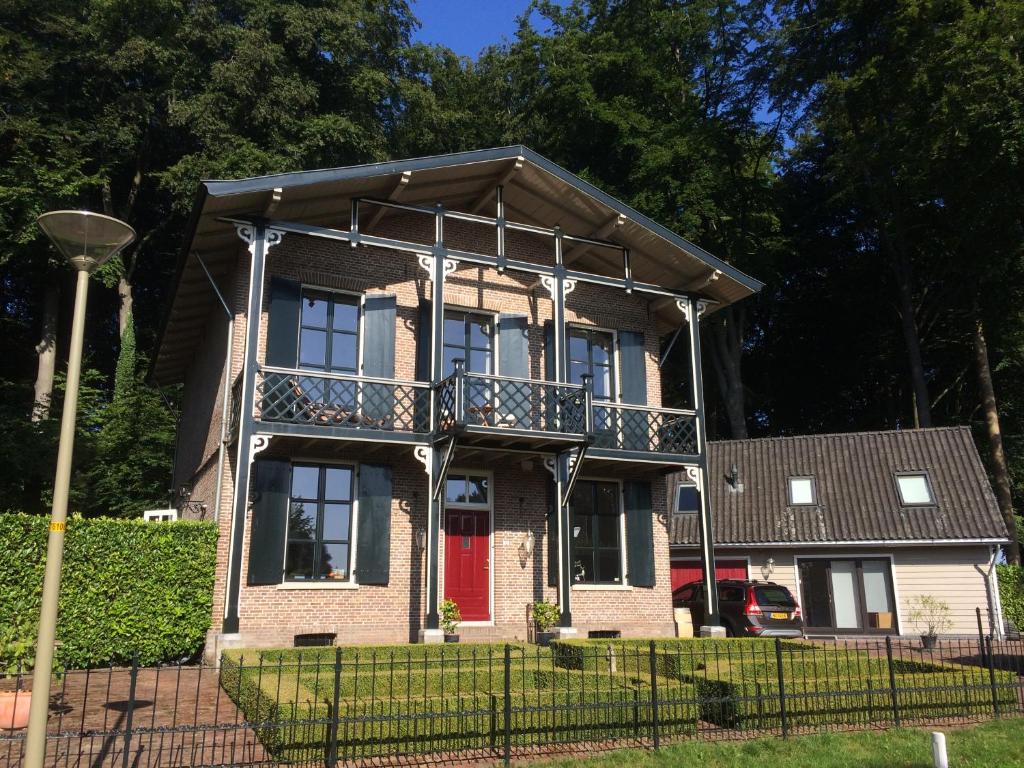 een bakstenen huis met een balkon en een rode deur bij B&B Woudzicht Groesbeek in Groesbeek
