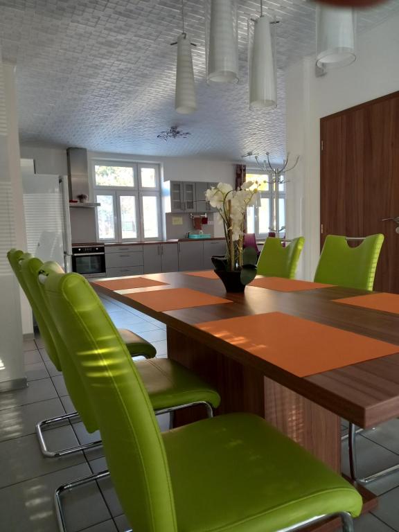a kitchen with a wooden table and green chairs at Alegria Natur Apartments in Mikulov