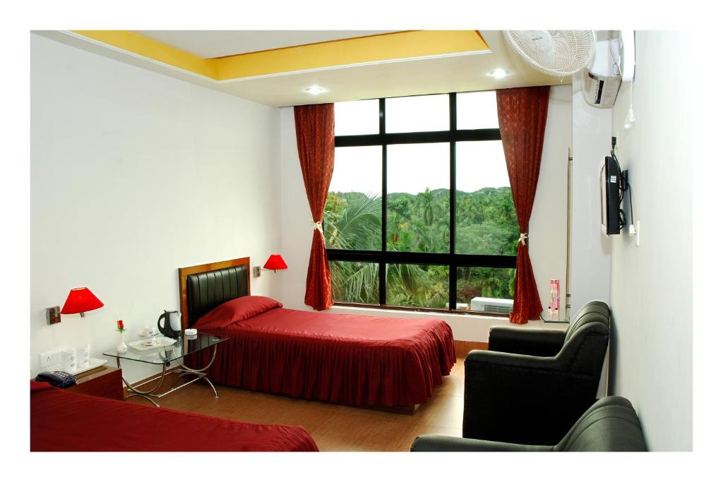 a bedroom with a red bed and a large window at Hotel Dooars Mountain in Alīpur Duār