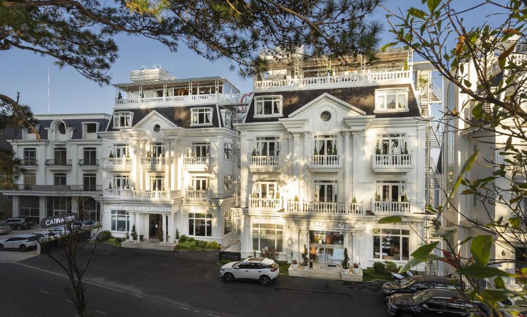 a white building with a car parked in front of it at New Life Hotel - Da Lat in Da Lat