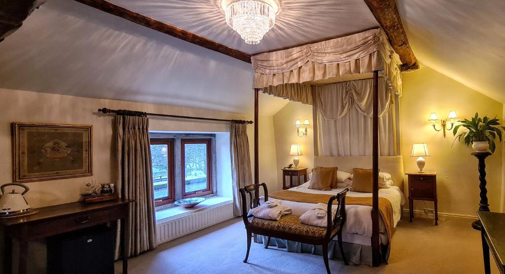 a bedroom with a canopy bed and a window at Biggin Hall Country House Hotel in Hartington