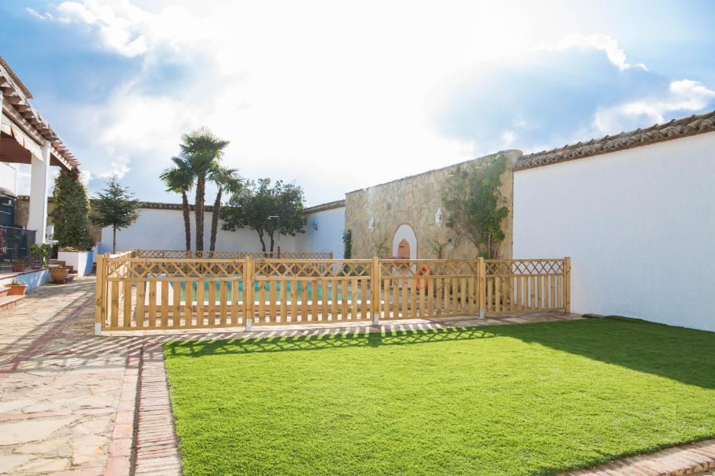 un patio con una valla de madera y césped en Casa Rural Aire, en Fuente de Piedra