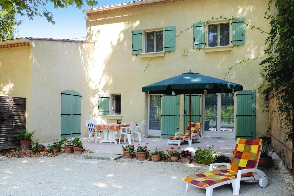 une terrasse avec des chaises et un parasol en face d'une maison dans l'établissement Semi-detached house, Beaucaire, à Beaucaire