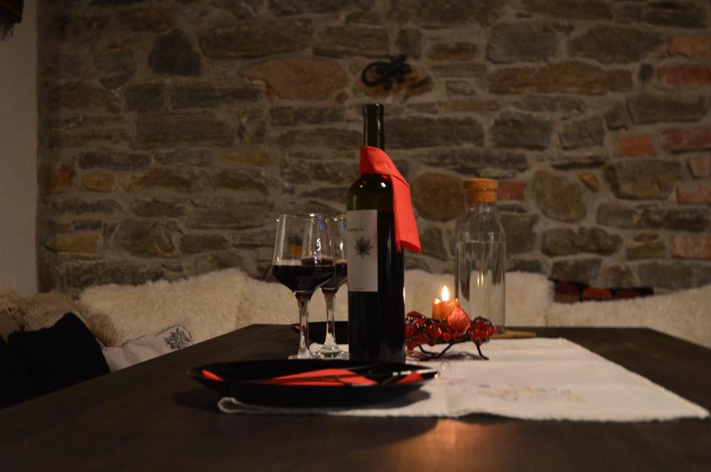 uma mesa com uma garrafa de vinho e dois copos em Yakusha - Якуша, къща за гости em Shiroka Lŭka