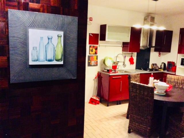 una cocina con mesa y una pintura de botellas en Comme Chez Soi 1 en Pointe-Noire