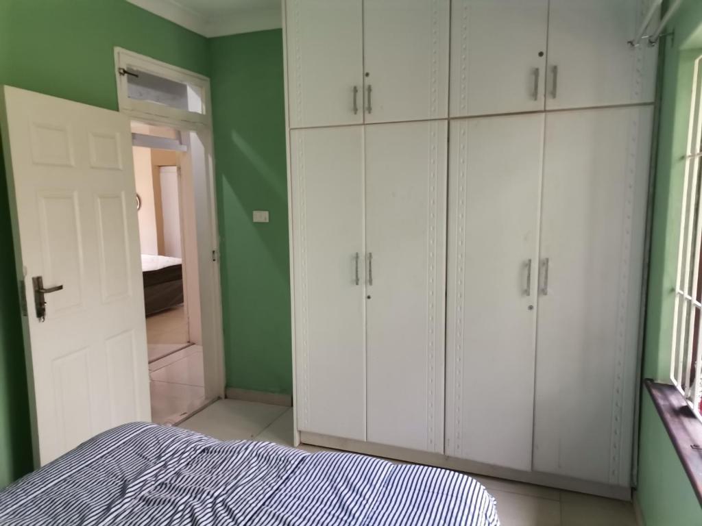 1 dormitorio con armarios blancos y una pared verde en Jackies Guest House, en Durban