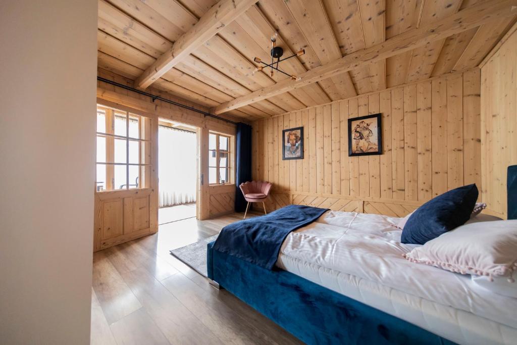 波羅寧的住宿－Atelier Jana Kasprowicza Apartamenty Stare Izby，一间带一张大床的卧室,位于带木墙的房间