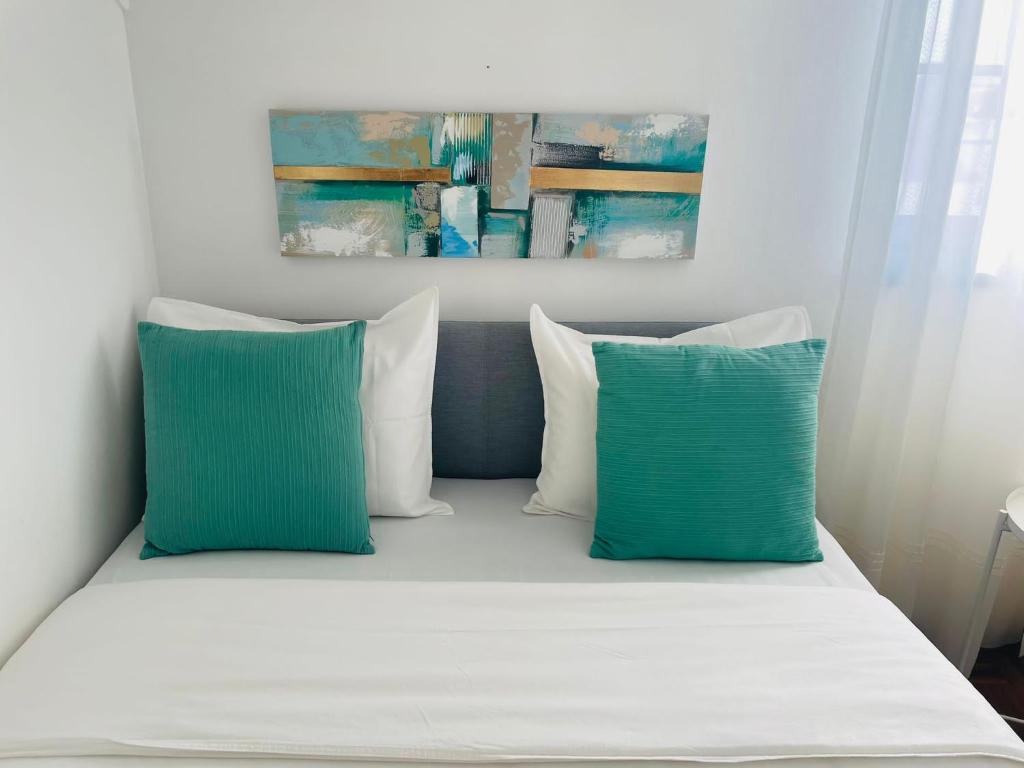 Bett mit blauen und weißen Kissen in einem Zimmer in der Unterkunft Besugo's House rooms & apartment in Nazaré