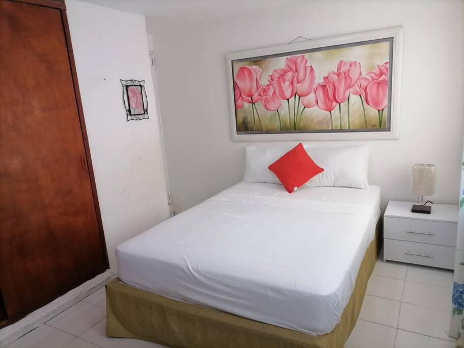 1 dormitorio con 1 cama con una pintura en la pared en Casa La Fe, en Cartagena de Indias