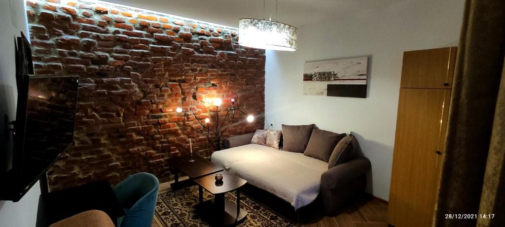 a living room with a couch and a brick wall at Confort Flat in Braşov