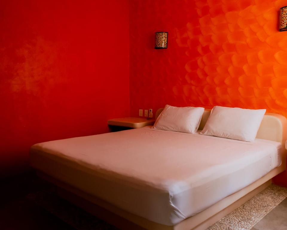 Zihuatanejo studio في زيهواتانيجو: غرفة نوم حمراء مع سرير بملاءات بيضاء