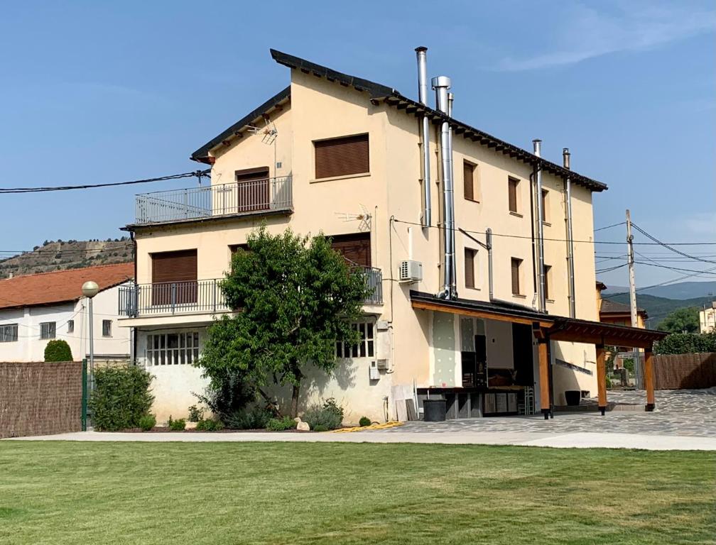 un grand bâtiment blanc avec un champ vert en face dans l'établissement Cal Canal, à Montferrer