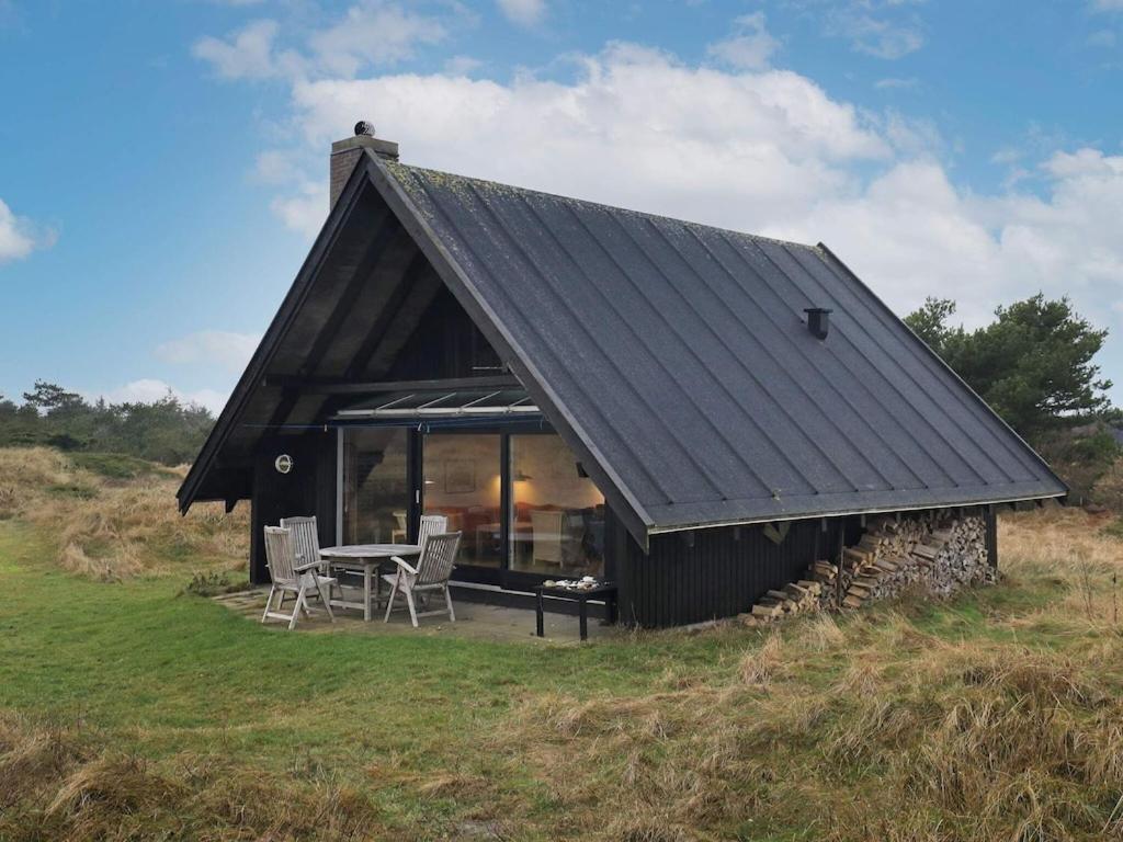 una casa negra con mesa y sillas en un campo en 6 person holiday home in Pandrup en Rødhus