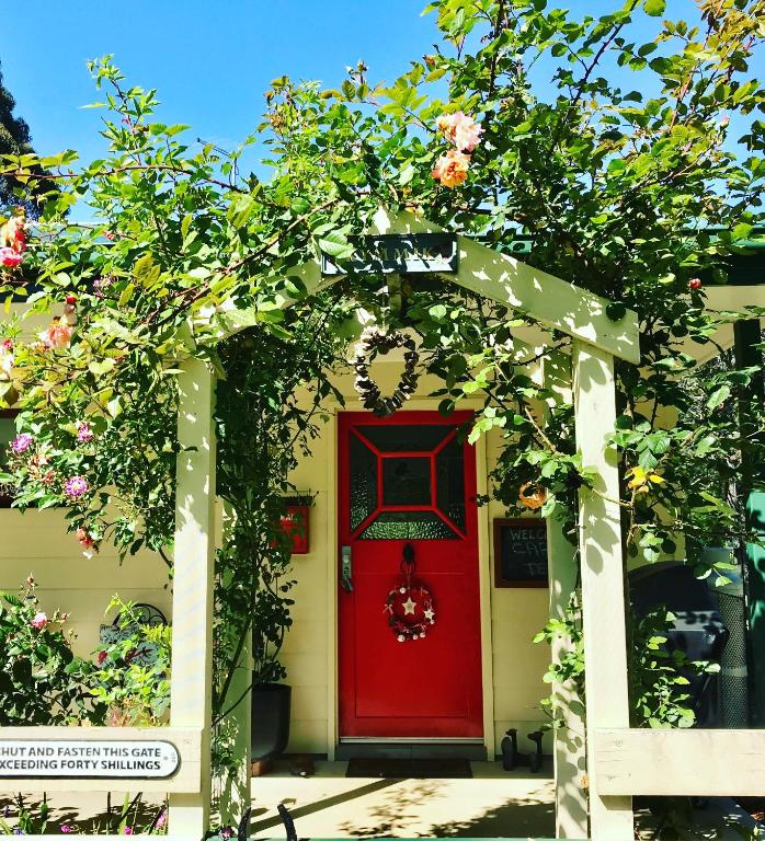 a red door on a white house with flowers at Kymmik Cottage in Geeveston