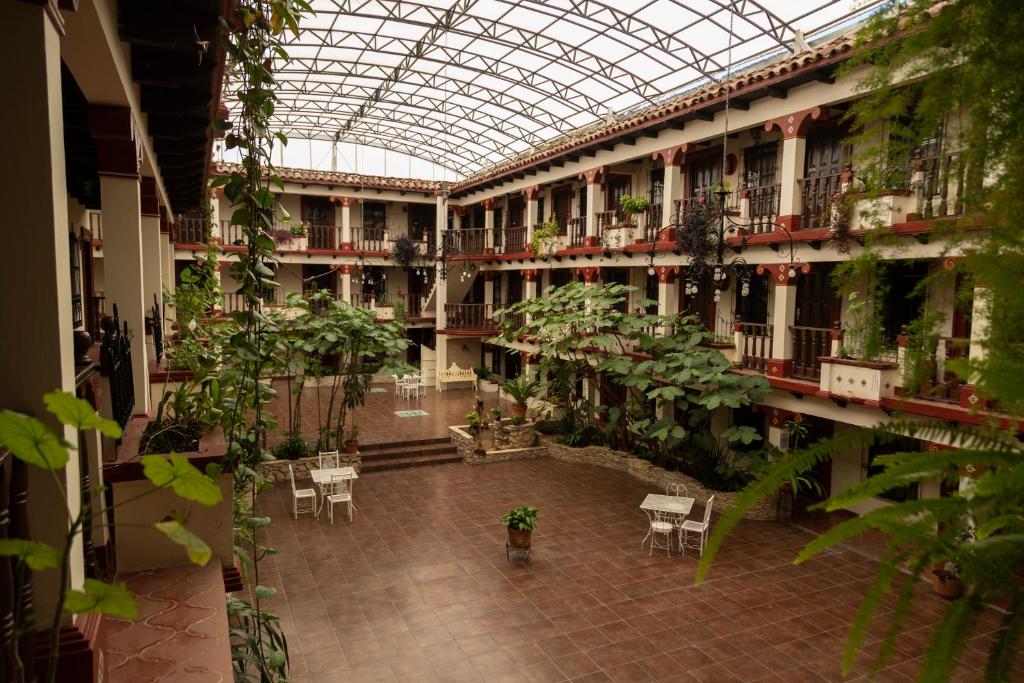 arium de un edificio con plantas, mesas y sillas en Hotel D’Monica en San Cristóbal de Las Casas