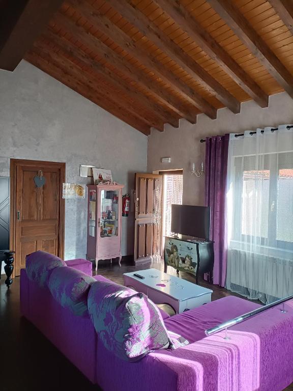 a living room with a purple couch and a tv at Esencia Mudayyan in Coca de Alba
