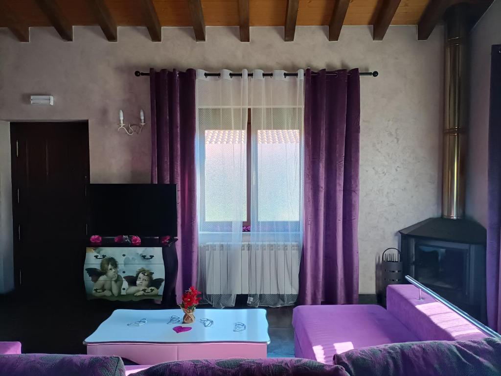 ein Wohnzimmer mit lila Vorhängen und einem Sofa in der Unterkunft Esencia Mudayyan in Coca de Alba