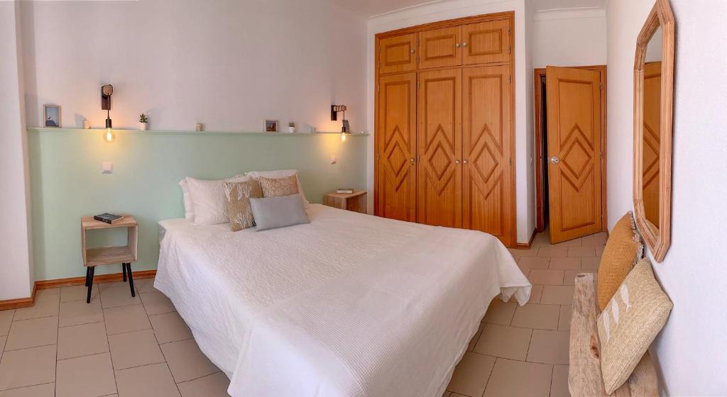 a bedroom with a white bed and a wooden door at Apartamentos Ninho das Gaivotas in Albufeira