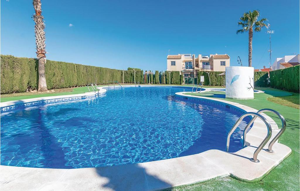 una grande piscina in un cortile con palme di Stunning Apartment In Torrevieja With Wifi, Outdoor Swimming Pool And Swimming Pool a Torrevieja