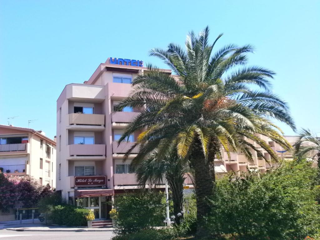 una palma di fronte a un edificio di Hôtel Maya a Cavalaire-sur-Mer