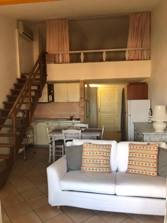 een woonkamer met een witte bank en een keuken bij Seahouse Portorotondo in Porto Rotondo