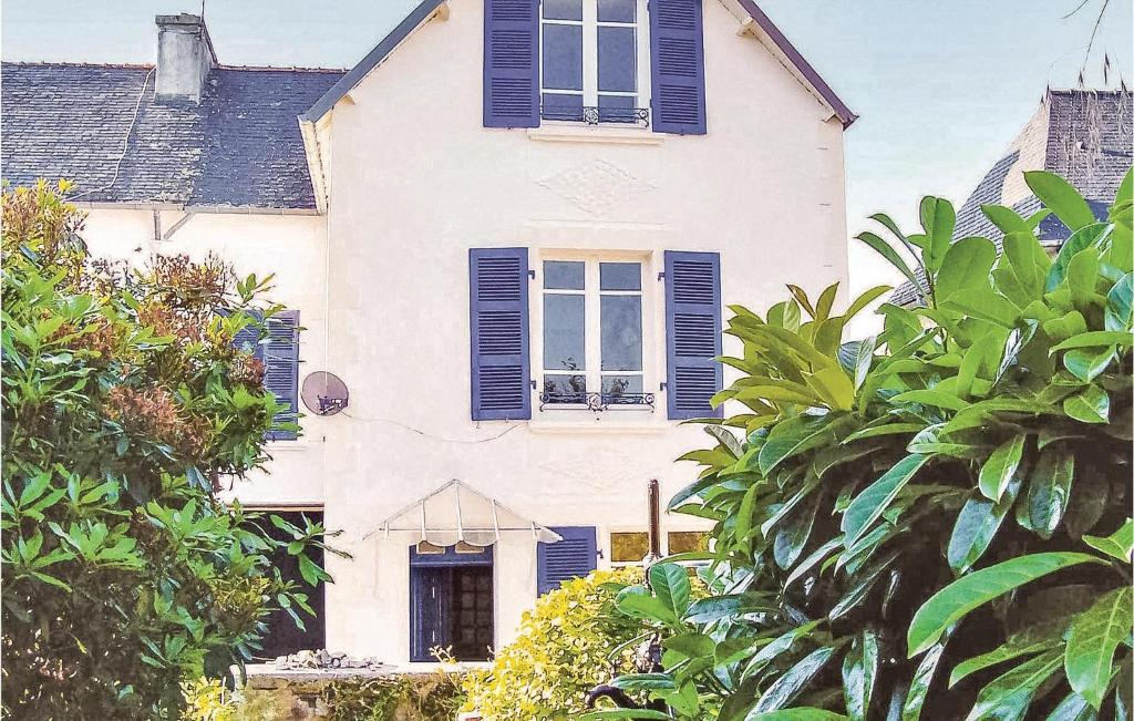 Casa blanca con ventanas con persianas azules y árboles en Lovely Home In Chateauneuf Du Faou With Wifi, en Saint-Thois