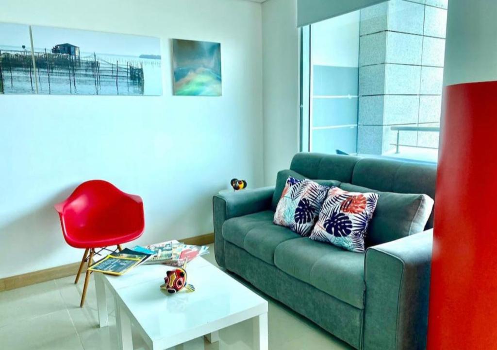 een woonkamer met een blauwe bank en een rode stoel bij Apartamento Moderno en Sector Norte de Barranquilla in Barranquilla
