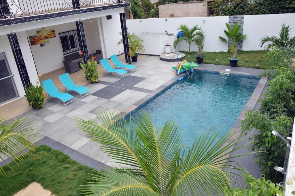 vista sul soffitto di una piscina con sedie blu di Magnifique villa climatisée avec piscine à Warang - Villa Keur Damel et Linguère a Ouoran